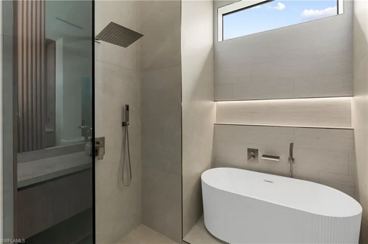 Bathroom featuring tile walls, a freestanding bath, and a walk in shower