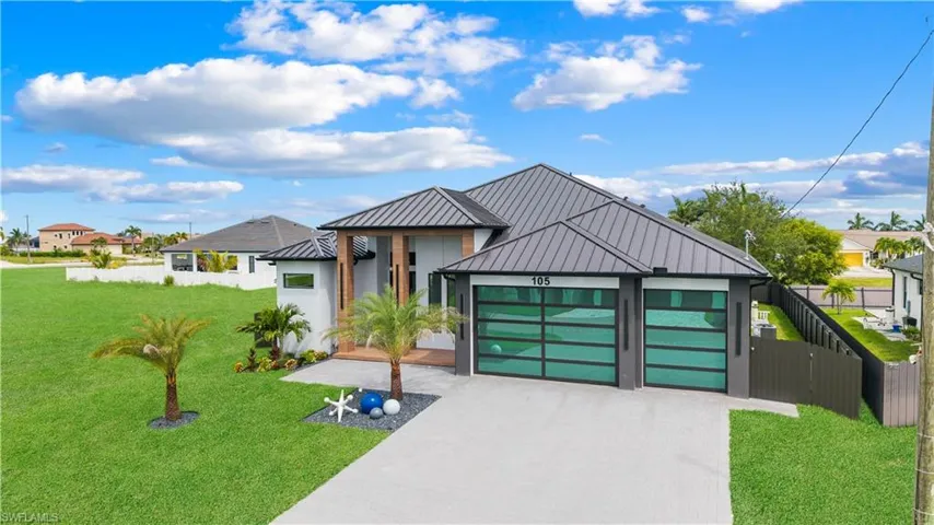 Contemporary house featuring concrete driveway, a standing seam roof, a metal roof, an attached garage, and stucco siding
