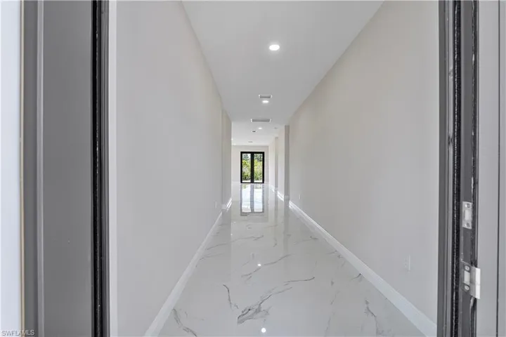 Corridor featuring recessed lighting and light marble finish floors