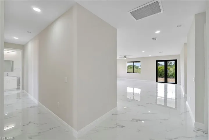 Hallway featuring recessed lighting, light marble finish flooring, and french doors