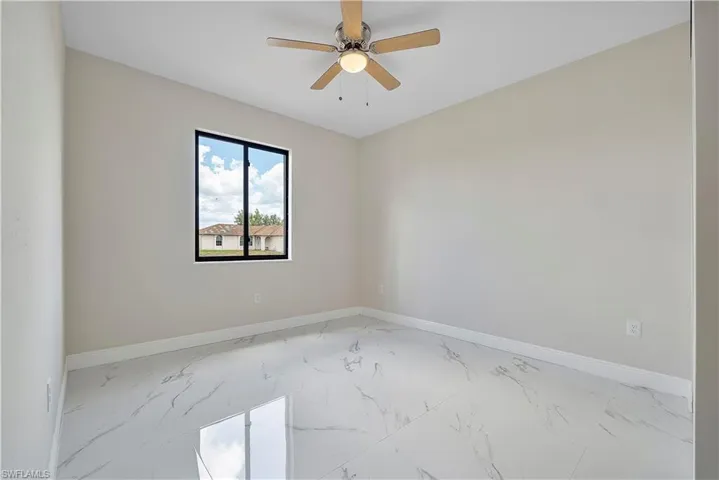 Spare room with light marble finish flooring and a ceiling fan
