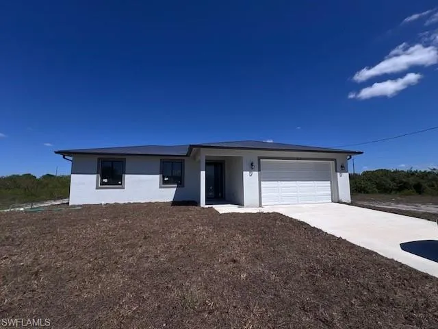 View of front facade featuring stucco siding, concrete driveway, and a garage