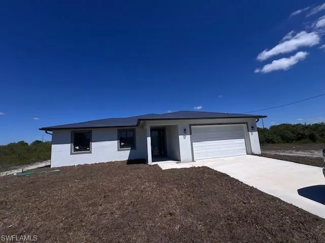 View of front facade with stucco siding, concrete driveway, and a garage
