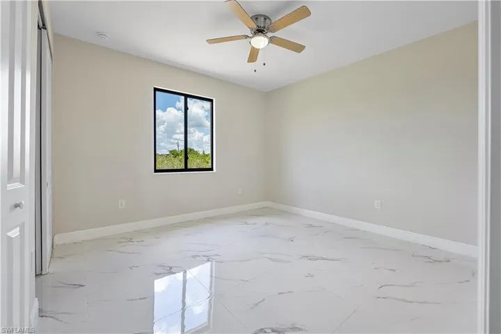 Spare room with light marble finish floors and ceiling fan