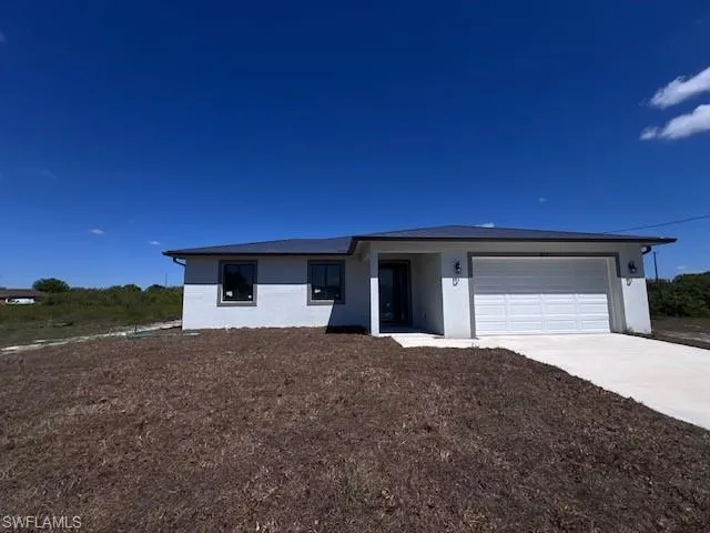 View of front of property with stucco siding, driveway, and a garage