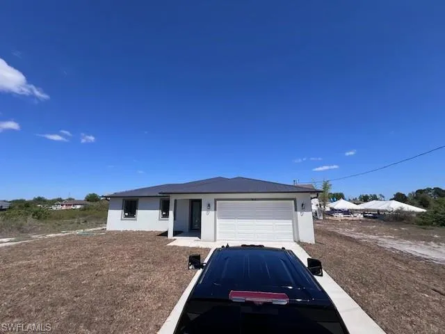 Ranch-style house featuring stucco siding, an attached garage, and a metal roof
