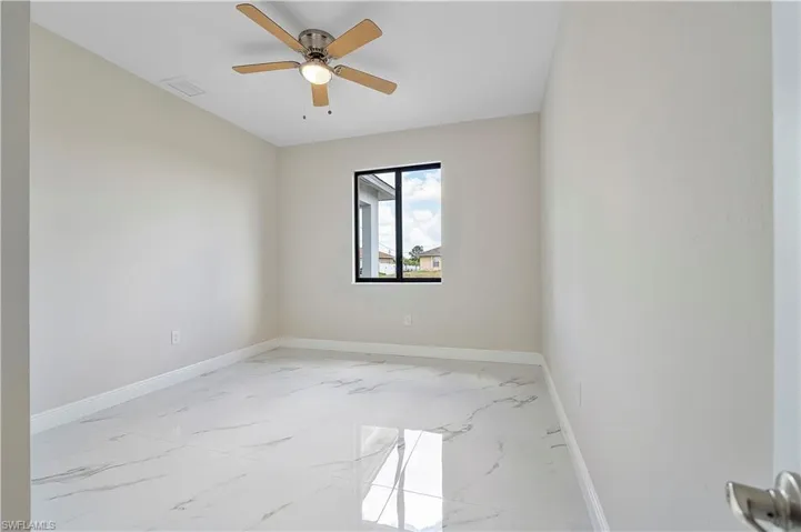 Empty room featuring light marble finish flooring and ceiling fan