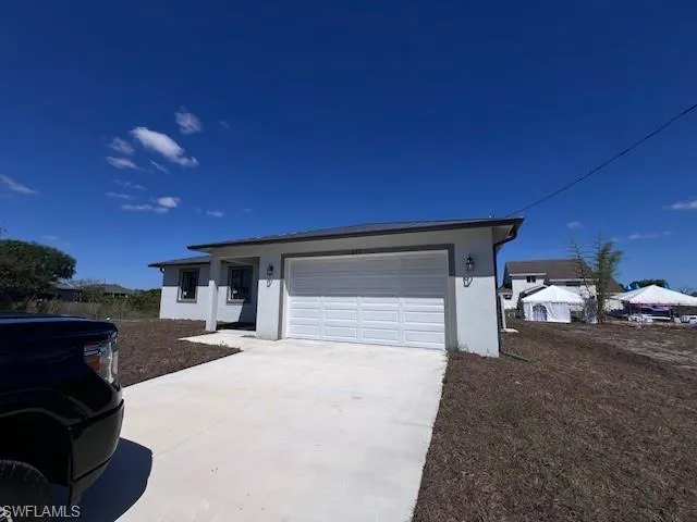 Single story home with stucco siding, driveway, and an attached garage