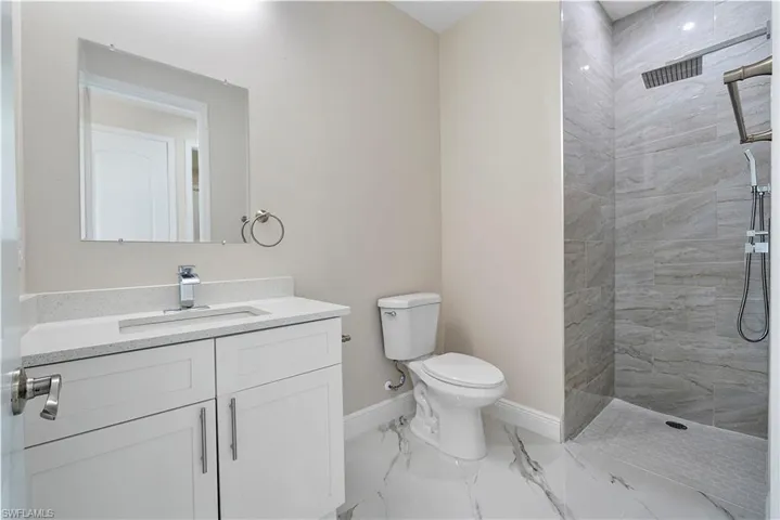 Full bath featuring a marble finish shower, vanity, and light marble finish floors