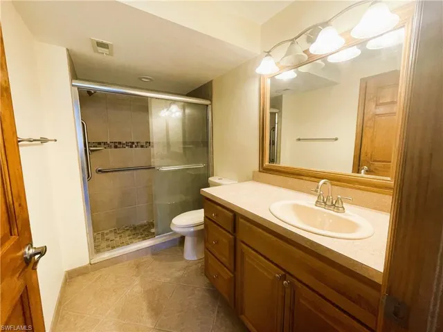Bathroom featuring vanity, light tile patterned floors, and a shower stall