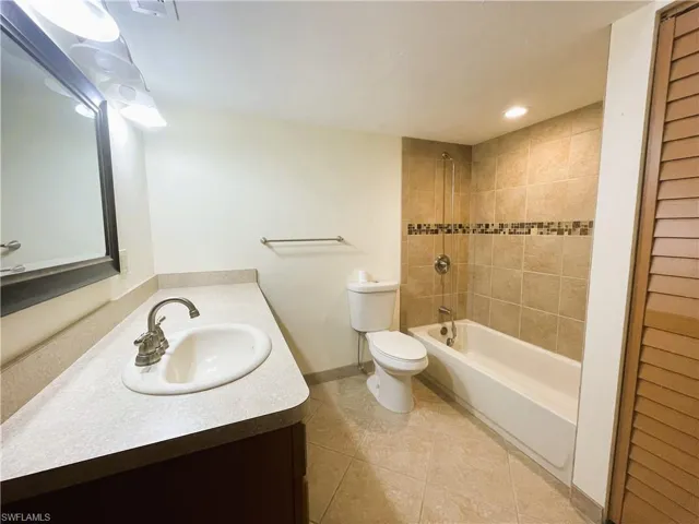 Bathroom with vanity, bathtub / shower combination, light tile patterned flooring, and recessed lighting