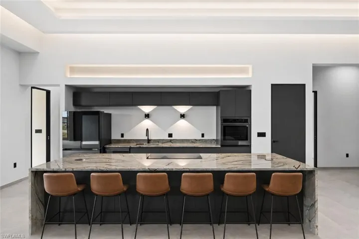 Kitchen featuring an expansive island with waterfall countertop, integrated cooktop, and seating for six