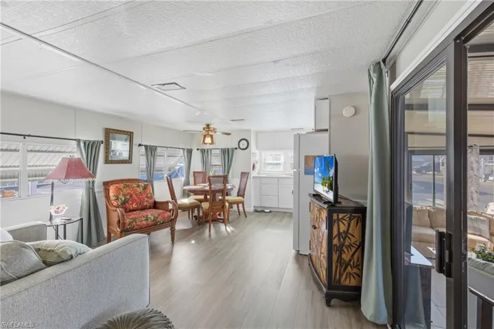 Living area featuring light wood finished floors, a textured ceiling, and ceiling fan