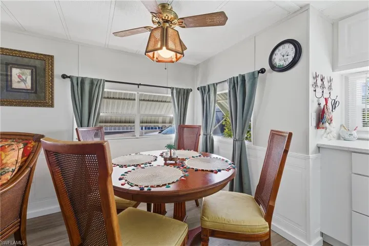 Dining area featuring a decorative wall, ceiling fan, wood finished floors, and a wainscoted wall
