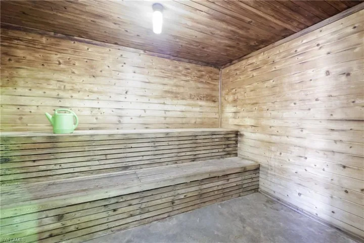 Relaxing sauna with unfinished concrete flooring, wooden walls, and wood ceiling