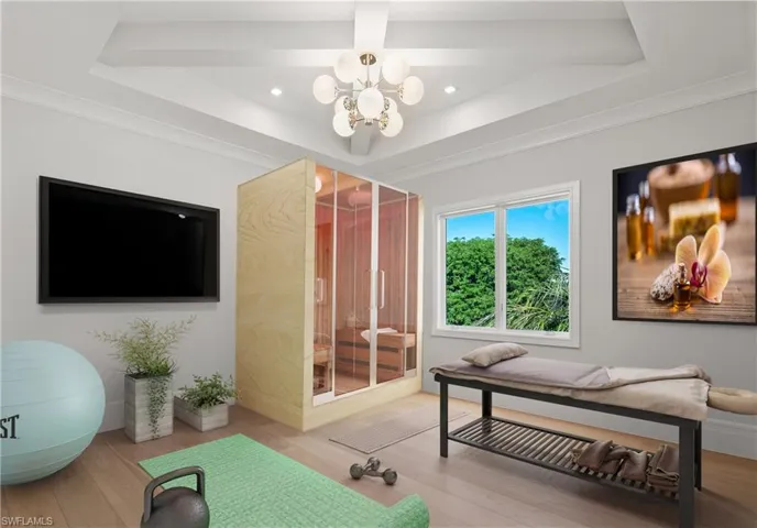 Bedroom featuring a tray ceiling, crown molding, an inviting chandelier, and wood-type flooring
