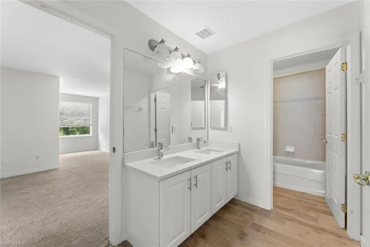 Second Floor guest bathroom with double vanity, tiled shower / bath, and plank tile floors