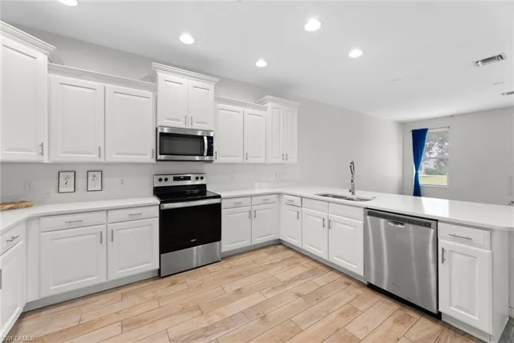 Kitchen featuring stainless steel appliances, white cabinets, kitchen peninsula, and sink