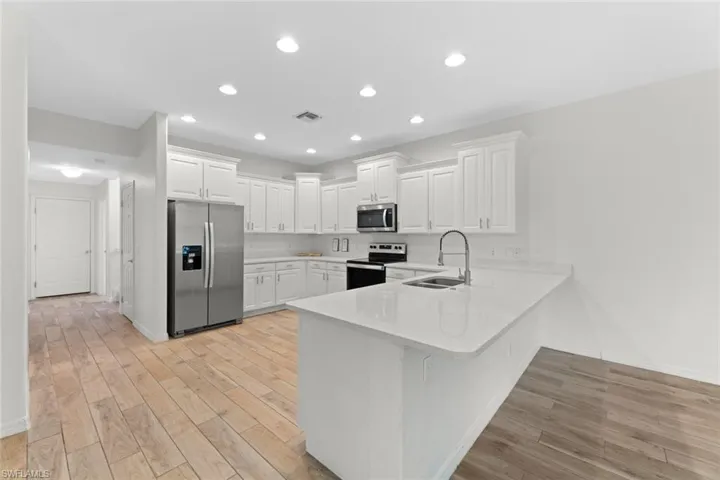 Kitchen peninsula, sink, white cabinets, and appliances with stainless steel finishes