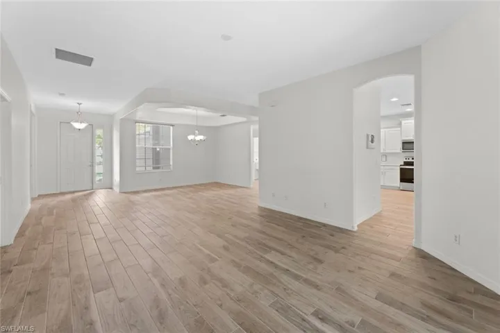 Unfurnished living room with light hardwood / wood-style floors and a notable chandelier