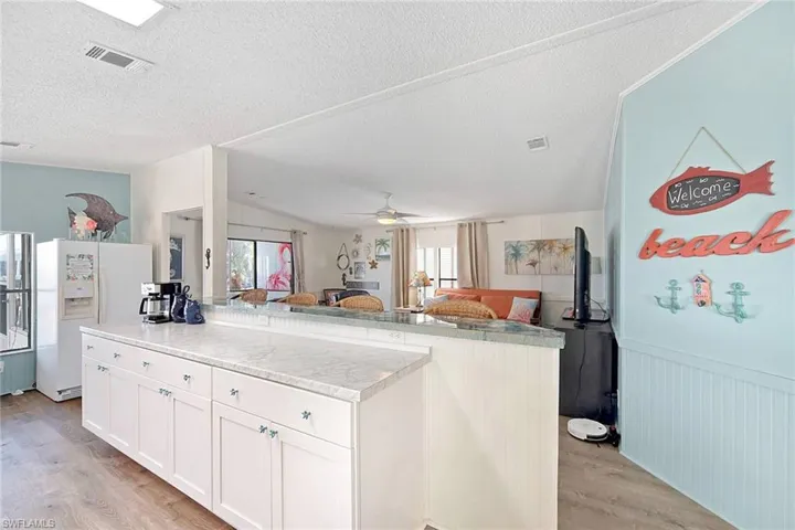 Kitchen with white refrigerator with ice dispenser, light countertops, open floor plan, light wood-style flooring, and a kitchen island