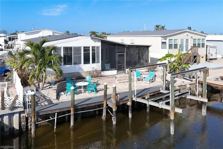 Dock featuring boat lift, a water view, a patio area, and a sunroom