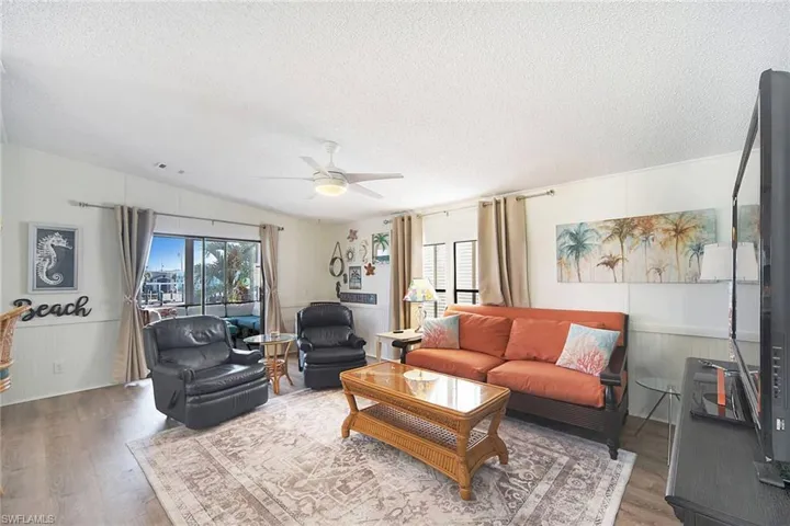 Living area featuring a wainscoted wall, wood finished floors, a textured ceiling, ceiling fan, and wood walls
