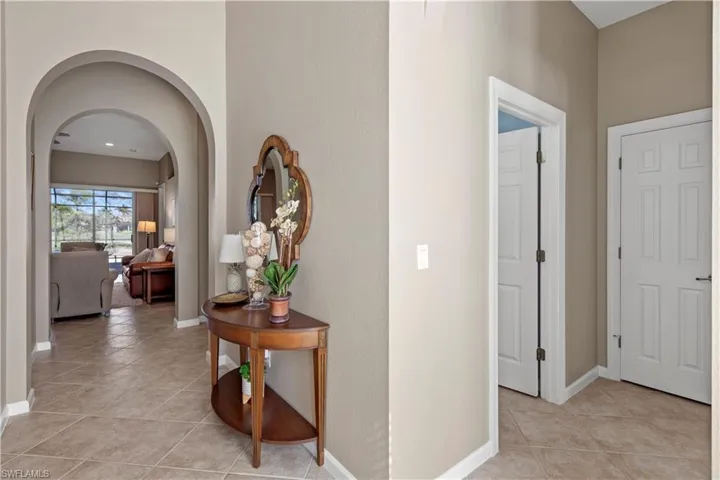 Hallway with arched walkways and light tile patterned floors