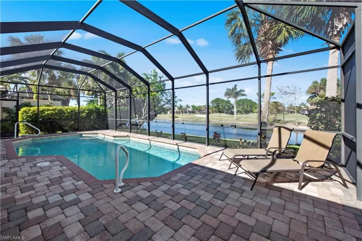 Swimming pool with a sunroom, a water view, glass enclosure, and a patio area