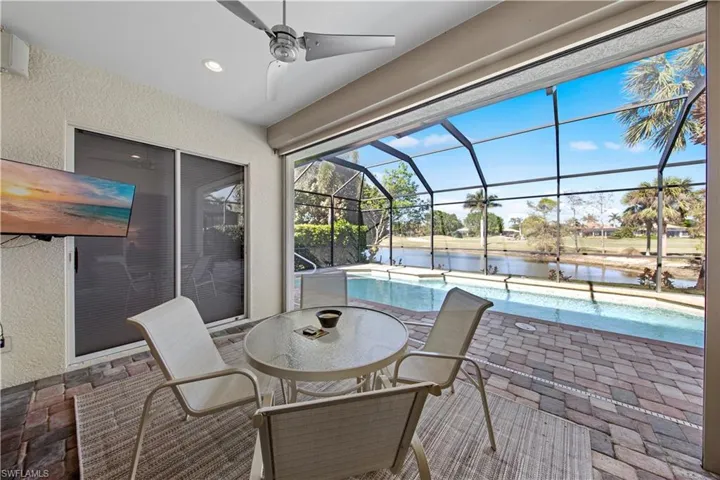 View of patio with an outdoor pool, a water view, glass enclosure, outdoor dining area, and a sunroom