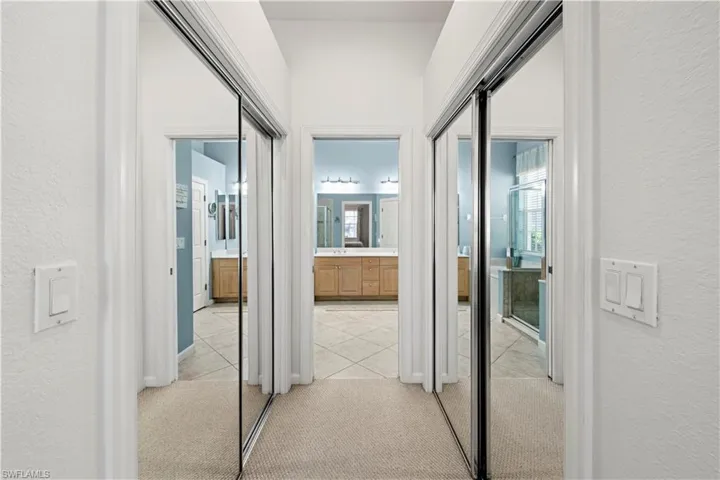 Hallway featuring a textured wall, light carpet, and light tile patterned flooring