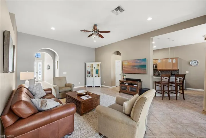 Living room featuring arched walkways, ceiling fan, light tile patterned floors, and recessed lighting