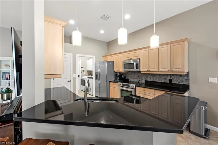 Kitchen featuring light brown cabinets, decorative light fixtures, decorative backsplash, and recessed lighting