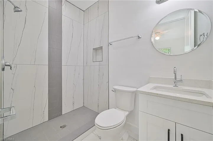Bathroom featuring a tile shower, vanity, and toilet