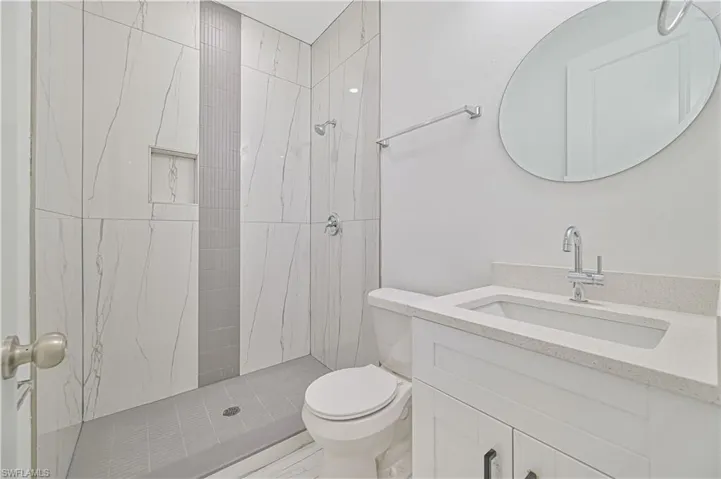 Bathroom with a tile shower, vanity, and toilet