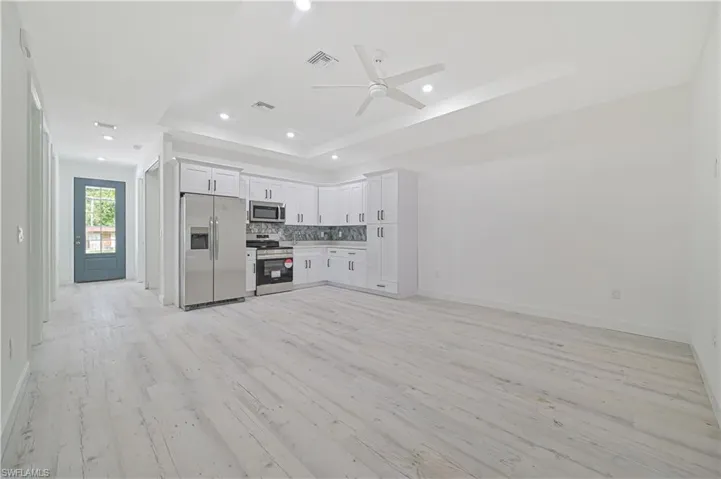 Unfurnished living room featuring a raised ceiling, light hardwood / wood-style floors, and ceiling fan