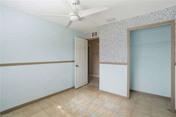 Unfurnished bedroom with ceiling fan, a closet, and wallpapered walls
