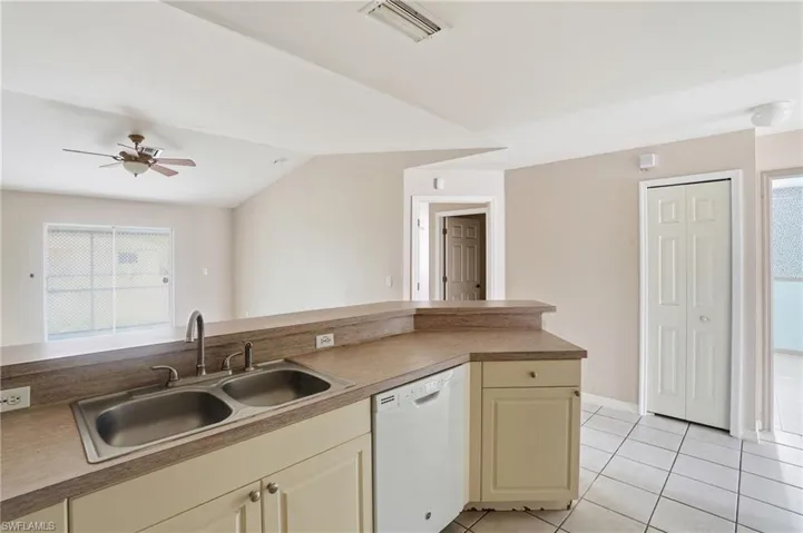 Kitchen featuring dishwasher, ceiling fan, cream cabinetry, light tile patterned floors, and light countertops