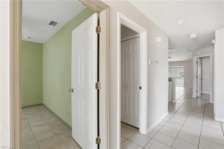 Hallway with light tile patterned flooring and baseboards