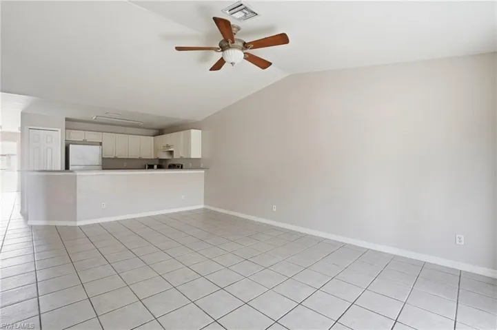 Unfurnished living room featuring a ceiling fan, light tile patterned floors, and lofted ceiling