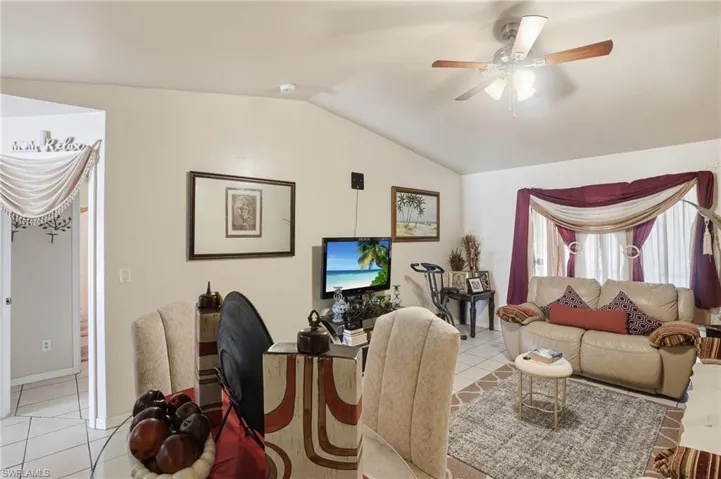 Living room featuring light tile patterned flooring, ceiling fan, and lofted ceiling