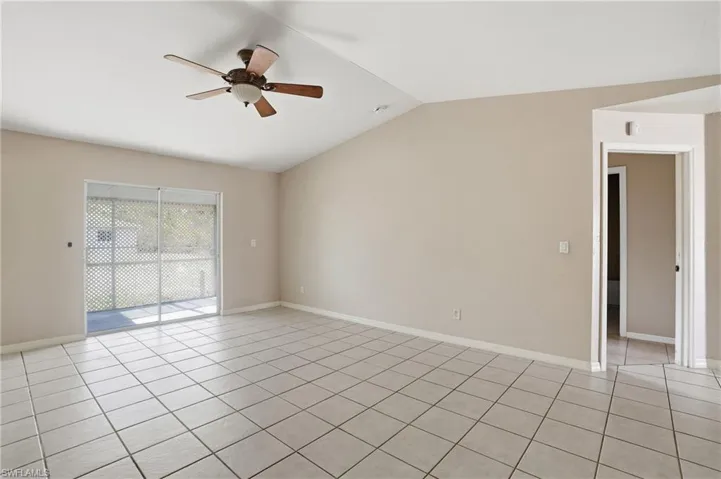 Unfurnished room featuring ceiling fan, lofted ceiling, and light tile patterned floors