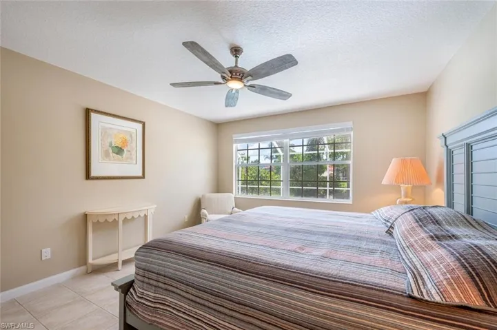 Bedroom with light tile patterned flooring, a textured ceiling, and ceiling fan
