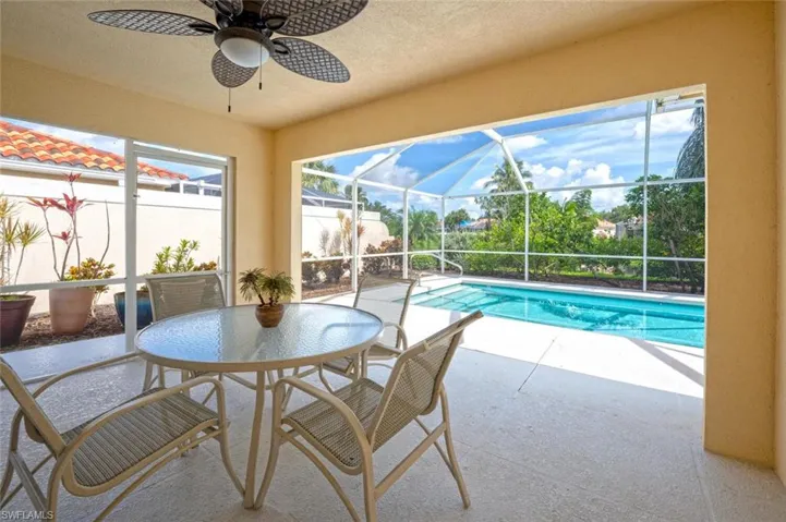View of pool featuring a patio, ceiling fan, and glass enclosure