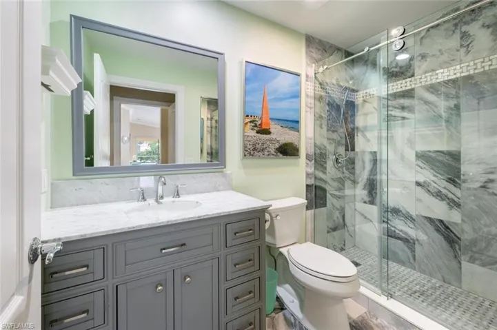 Bathroom featuring vanity, walk in shower, and toilet