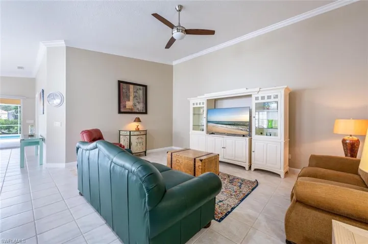 Tiled living room featuring ceiling fan and ornamental molding
