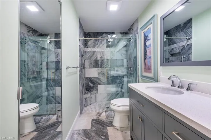 Bathroom featuring tile patterned floors, a shower with door, toilet, and vanity