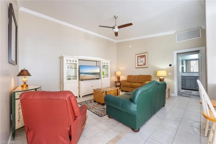 Tiled living room featuring crown molding and ceiling fan
