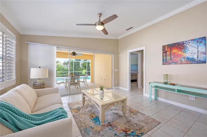 Living room featuring light tile patterned floors, ceiling fan, vaulted ceiling, and crown molding