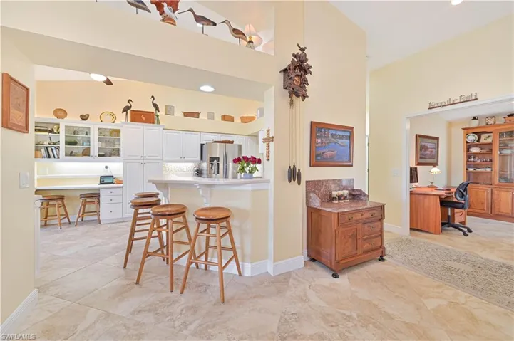 Kitchen featuring a kitchen bar, glass fronted cabinets, stainless steel fridge with ice dispenser, built in study area, and a peninsula